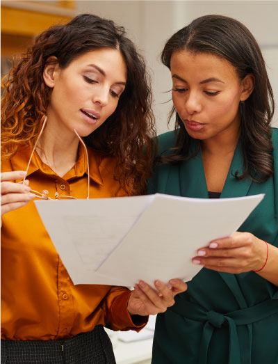 two women looking at a sheet of paper and discussing talent attraction