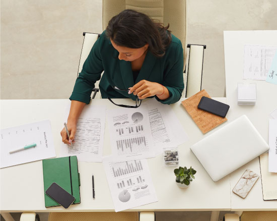 Woman at desk bird's eye view reviewing talent attraction articles