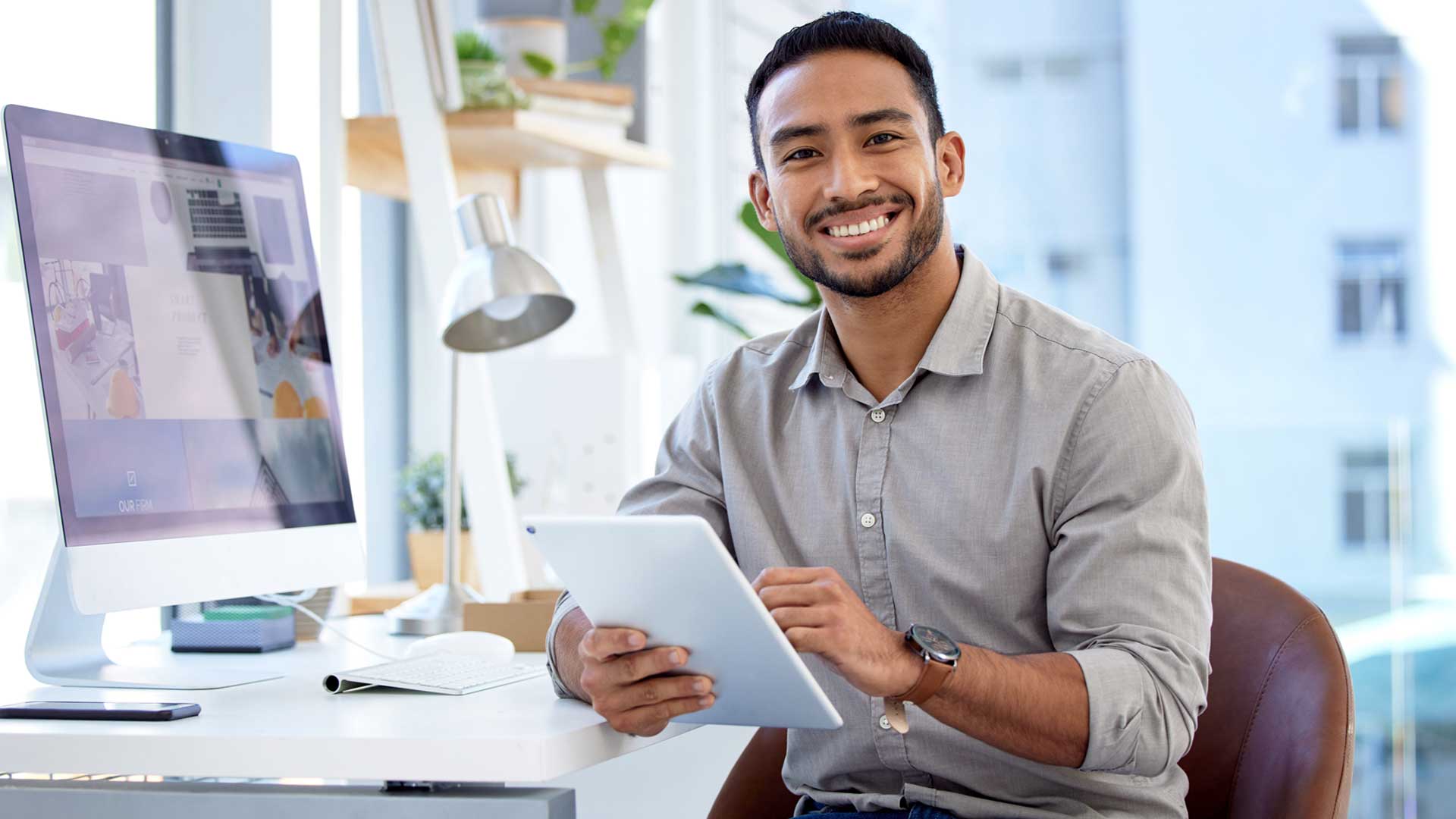 Young man holding tablet at office desk, reviewing Insights from his team