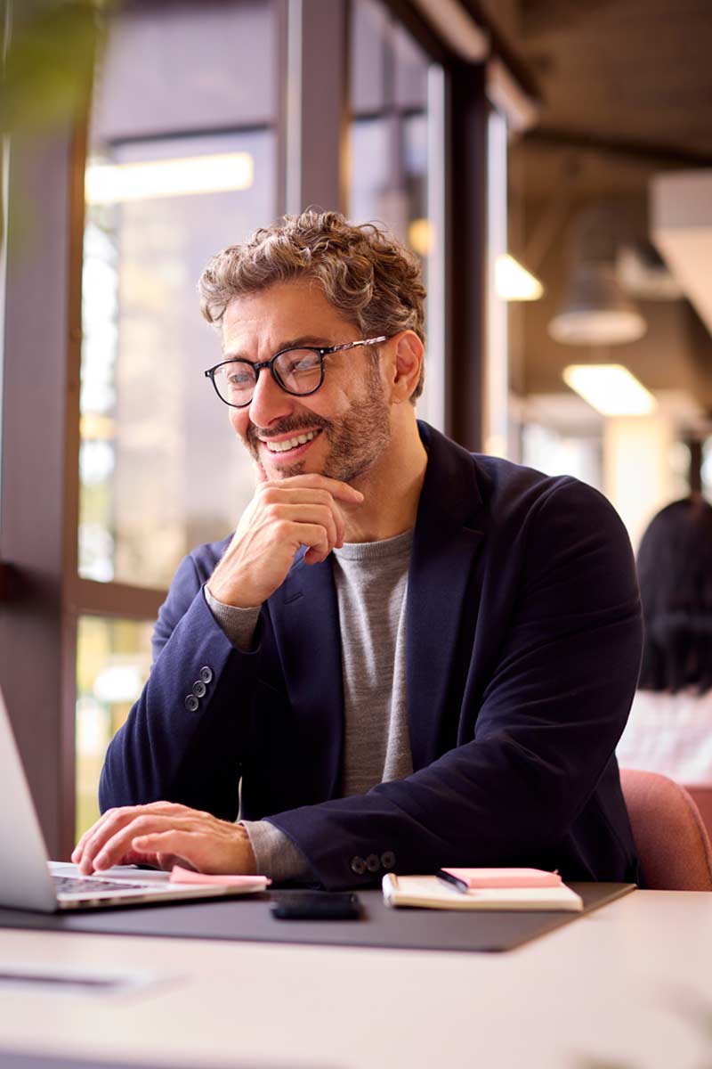 Man on laptop smiling in an office. Laptop running Fuel50's Talent Marketplace and Skills Ontology