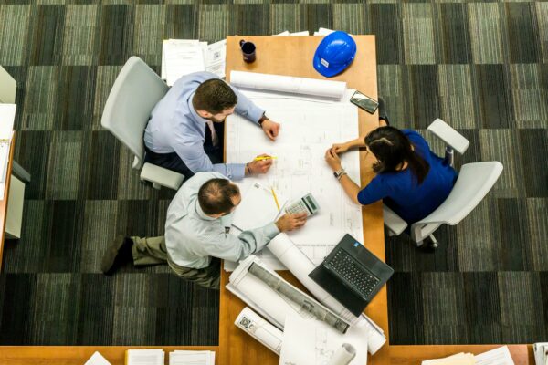 three business people sitting at a table with paper creating upskilling plan